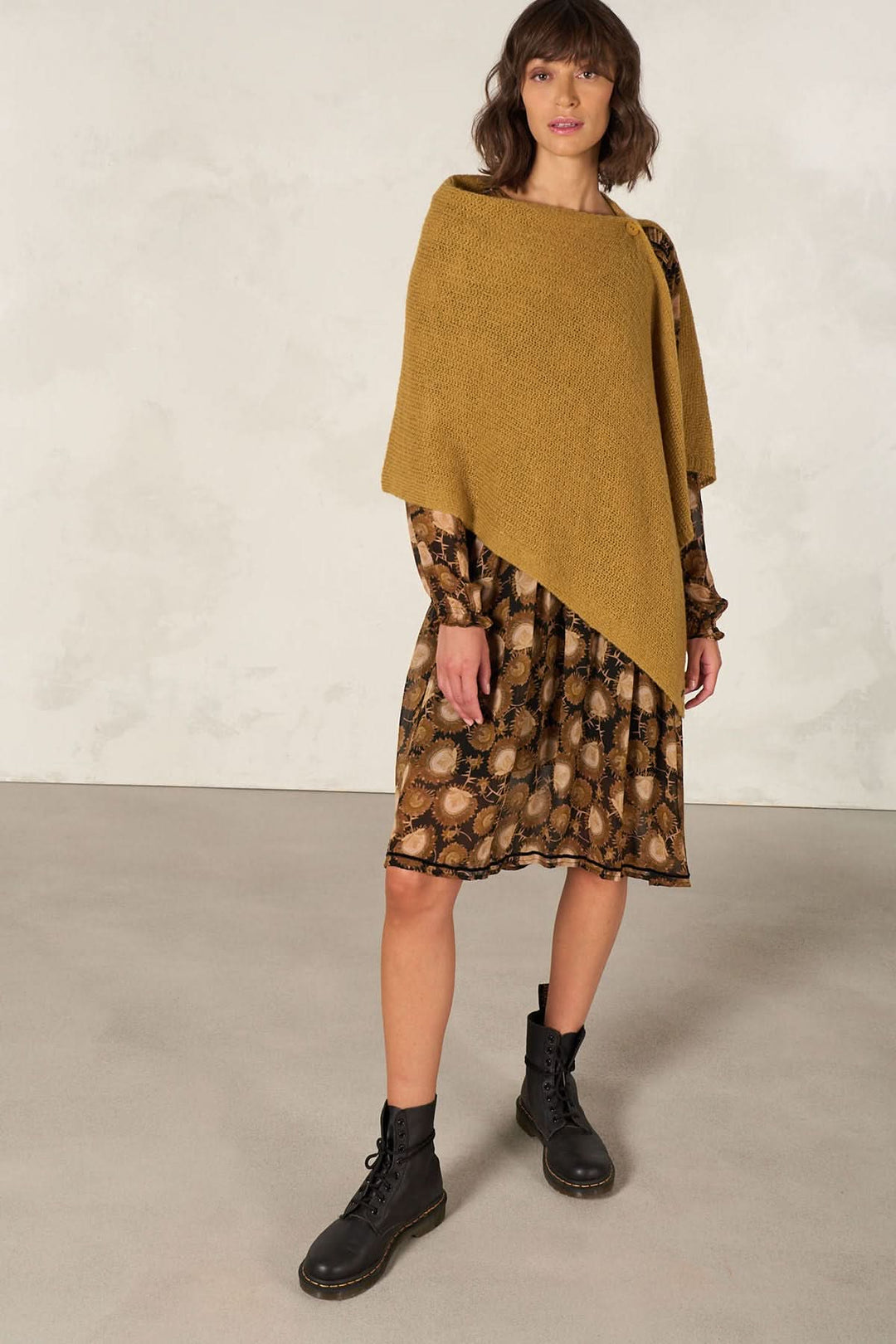 Cape foulard multifonctionnelle en tricot, portée sur une robe à motifs, style élégant et douillet.