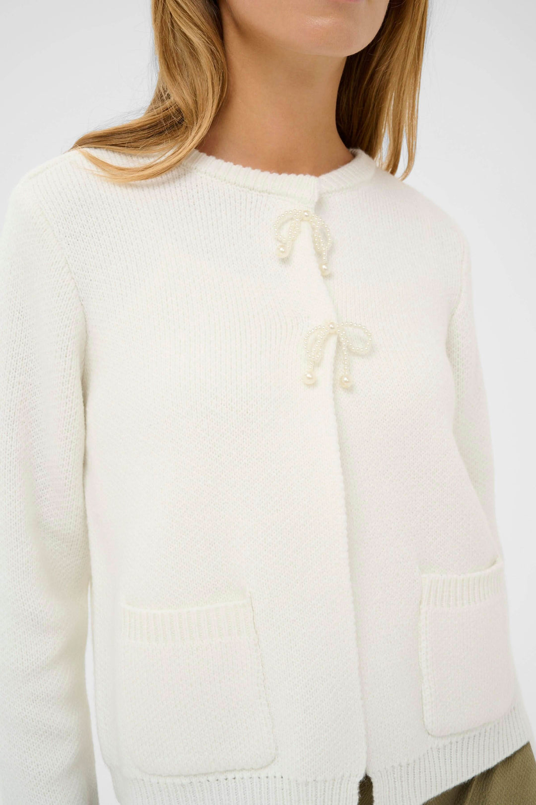Cardigan Bowie blanc avec liens décoratifs féminins pour un style élégant et intemporel, porté par un mannequin, vue de face.