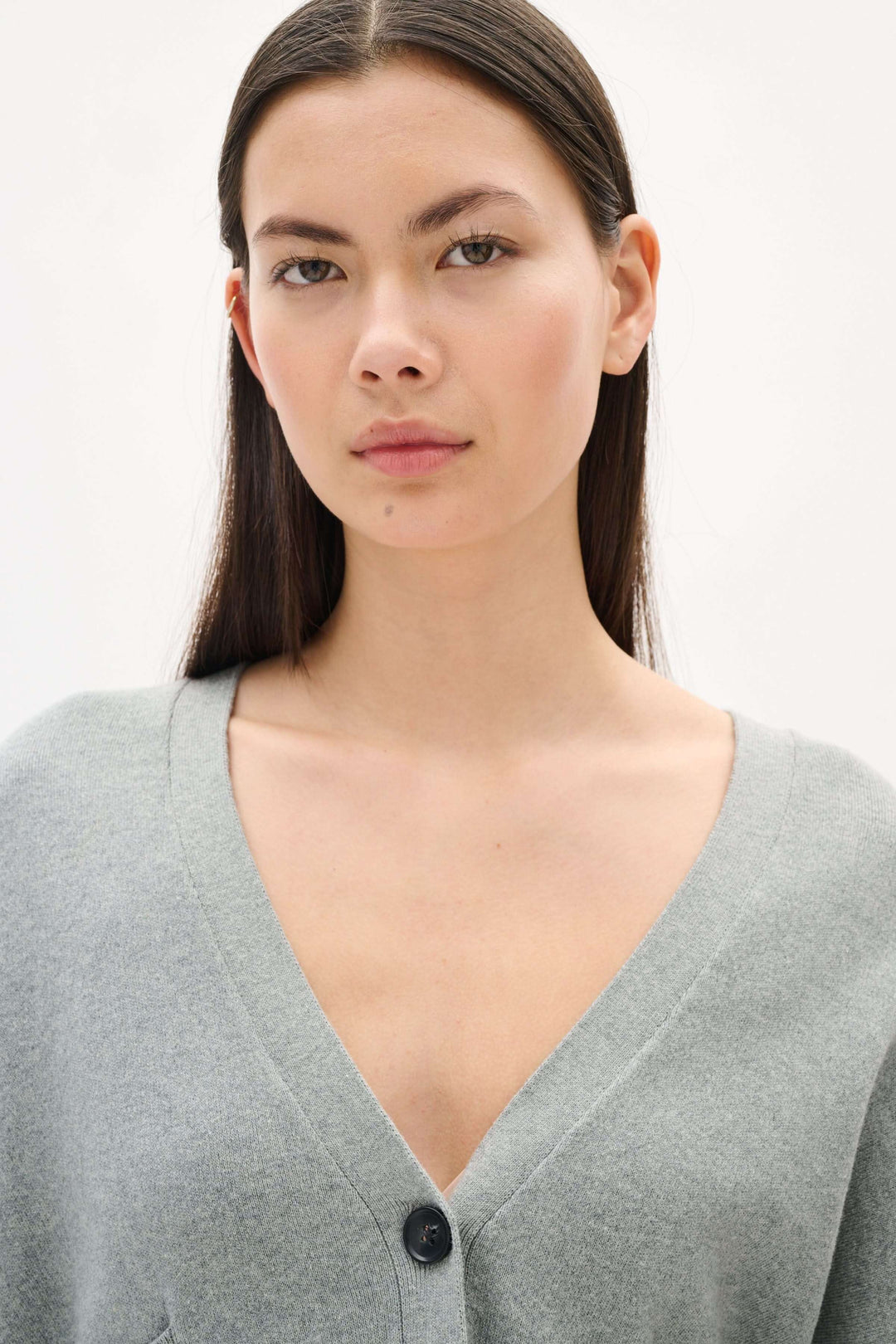 Femme portant un cardigan gris Tenley au design minimaliste avec encolure en V et boutons contrastants.