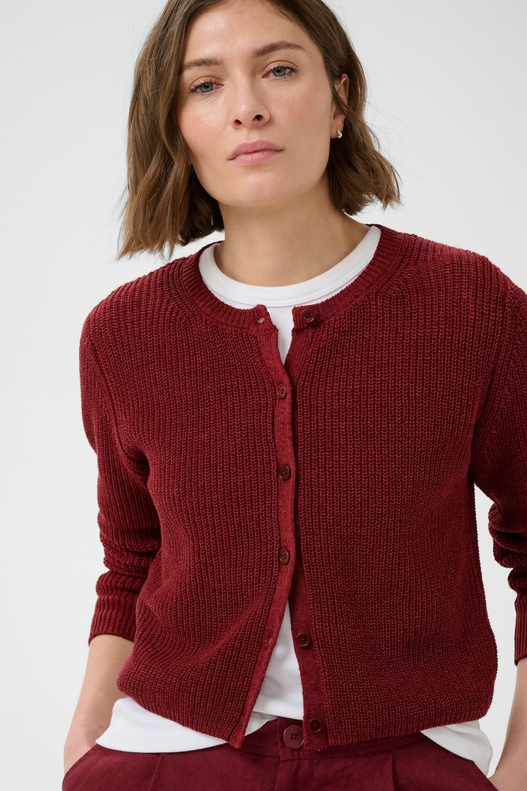 Femme portant le cardigan boutonné Gigia en maille texturée rouge, style décontracté avec encolure ronde et fermeture boutonnée.