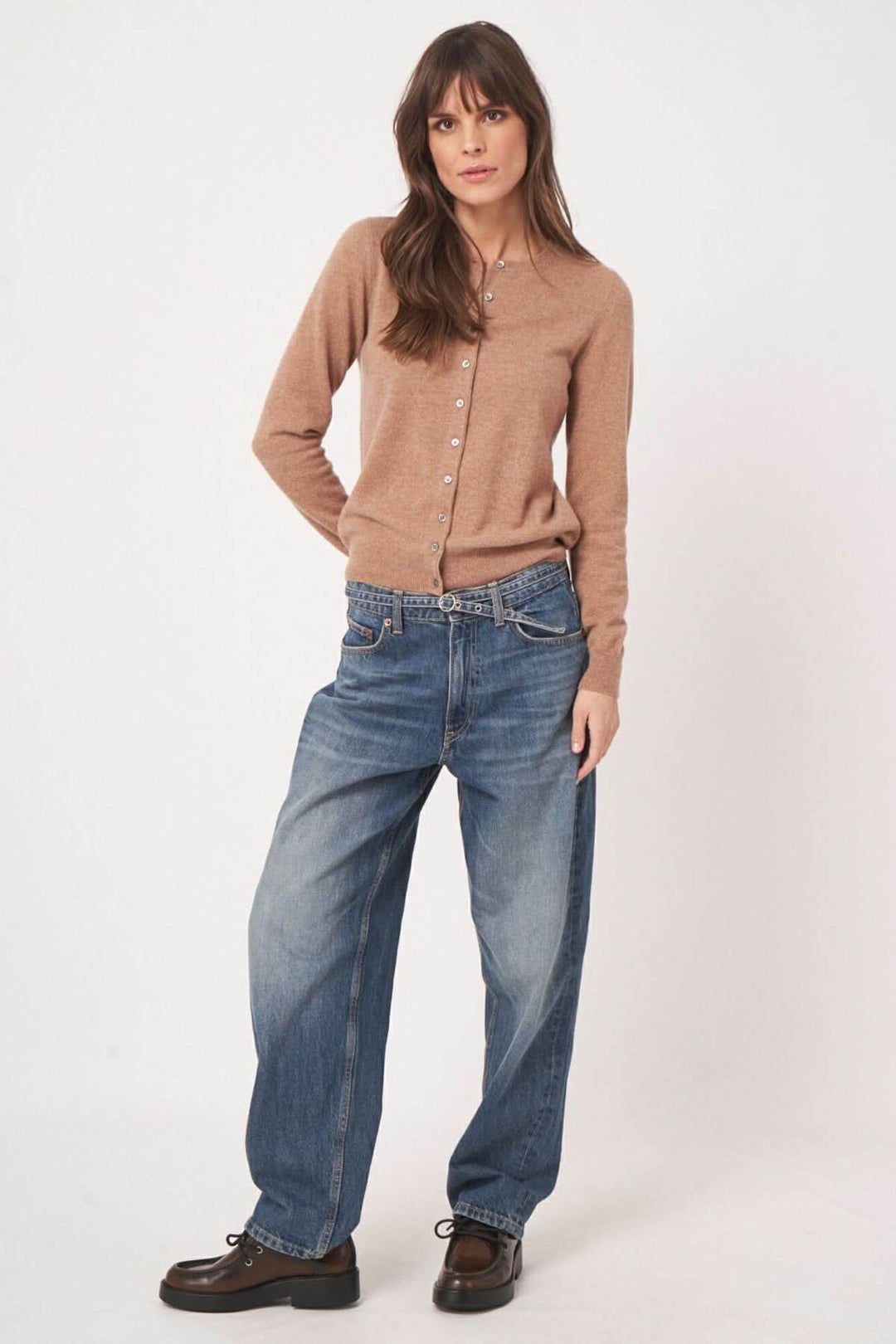 Femme portant un cardigan boutonné marron avec un pantalon en denim pour un look casual chic.