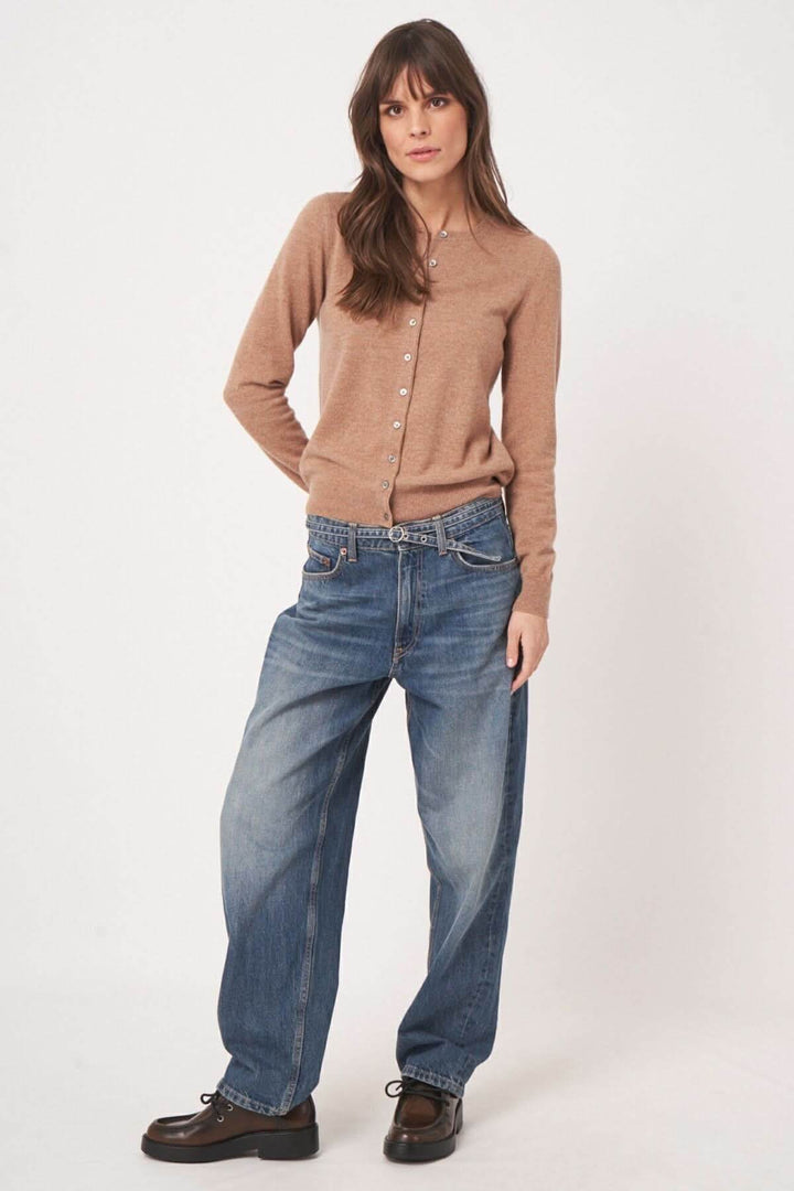 Femme portant un cardigan boutonné marron avec un pantalon en denim pour un look casual chic.
