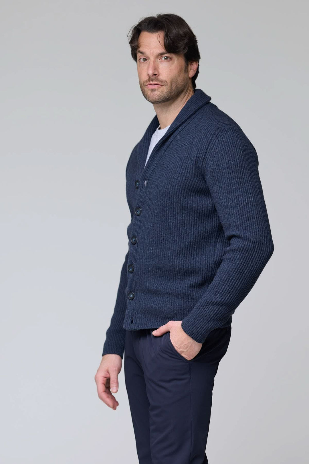 Homme portant un cardigan à col châle en laine bleu avec maille côtelée et fermeture à boutons, idéal pour superpositions élégantes.