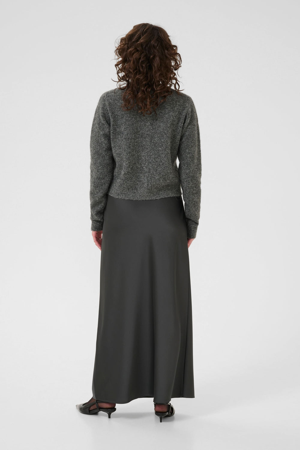 Femme portant un Cardigan en laine bouclée à col orné avec jupe satinée, vue de dos, style élégant et raffiné.