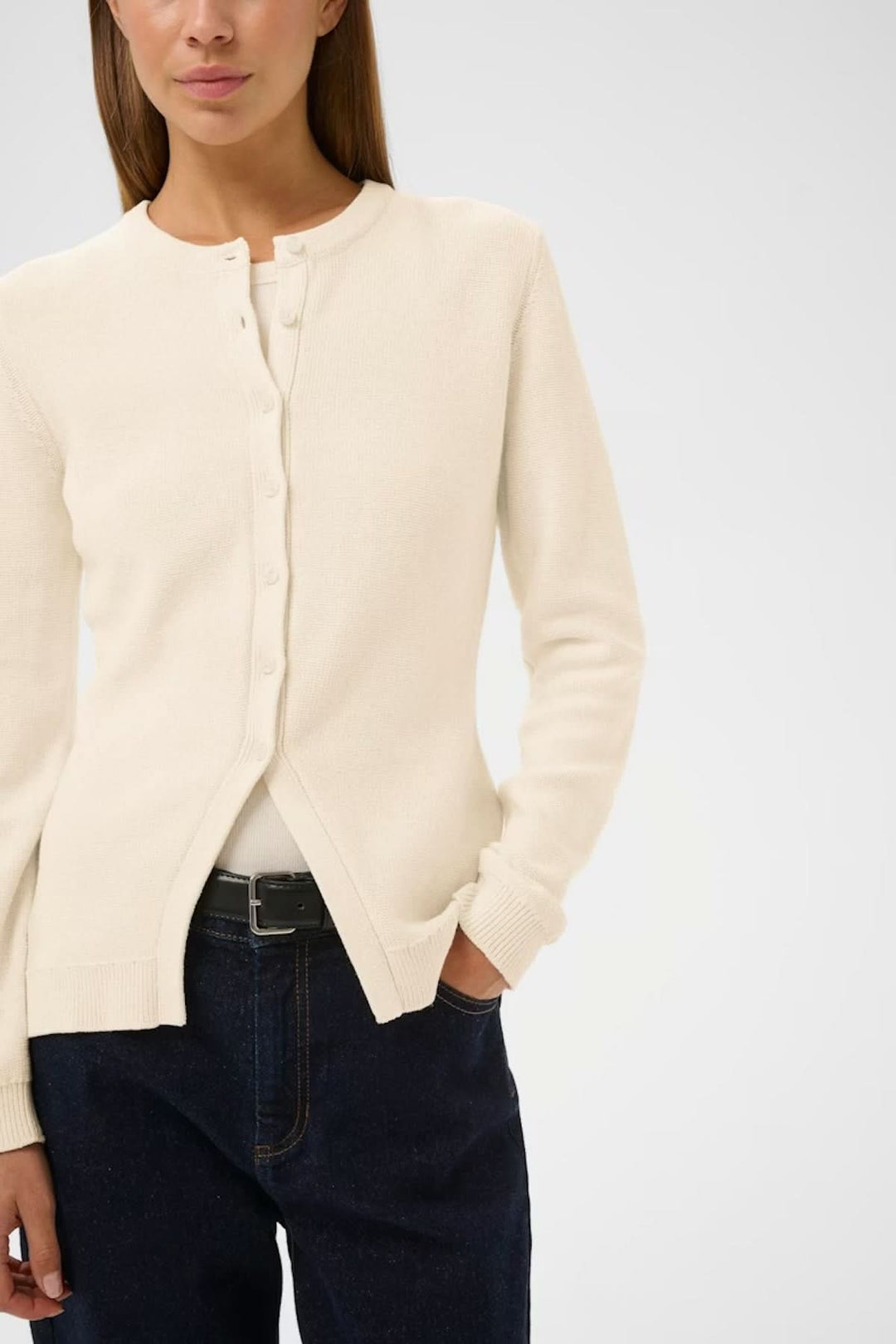 Cardigan en maille NAASU blanc, coupe droite, encolure arrondie, porté ouvert sur une tenue décontractée, style épuré élégant.