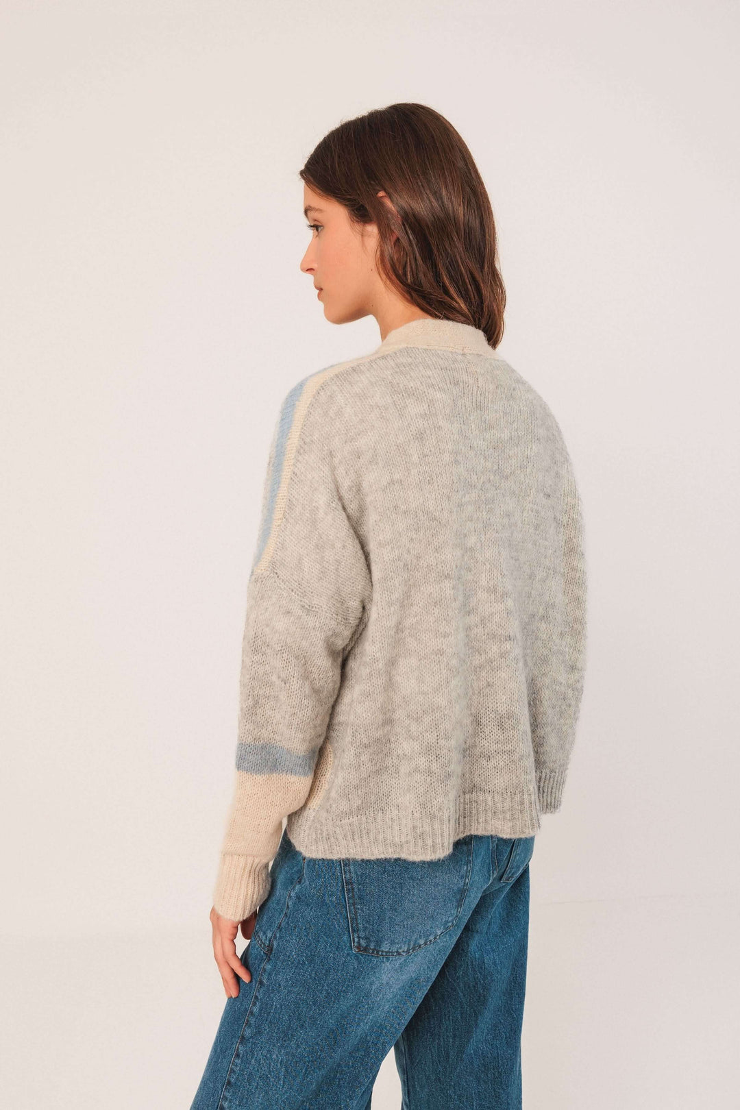 Cardigan en maille douce avec motif graphique et encolure en V, porté de dos, style décontracté, couleurs grises.