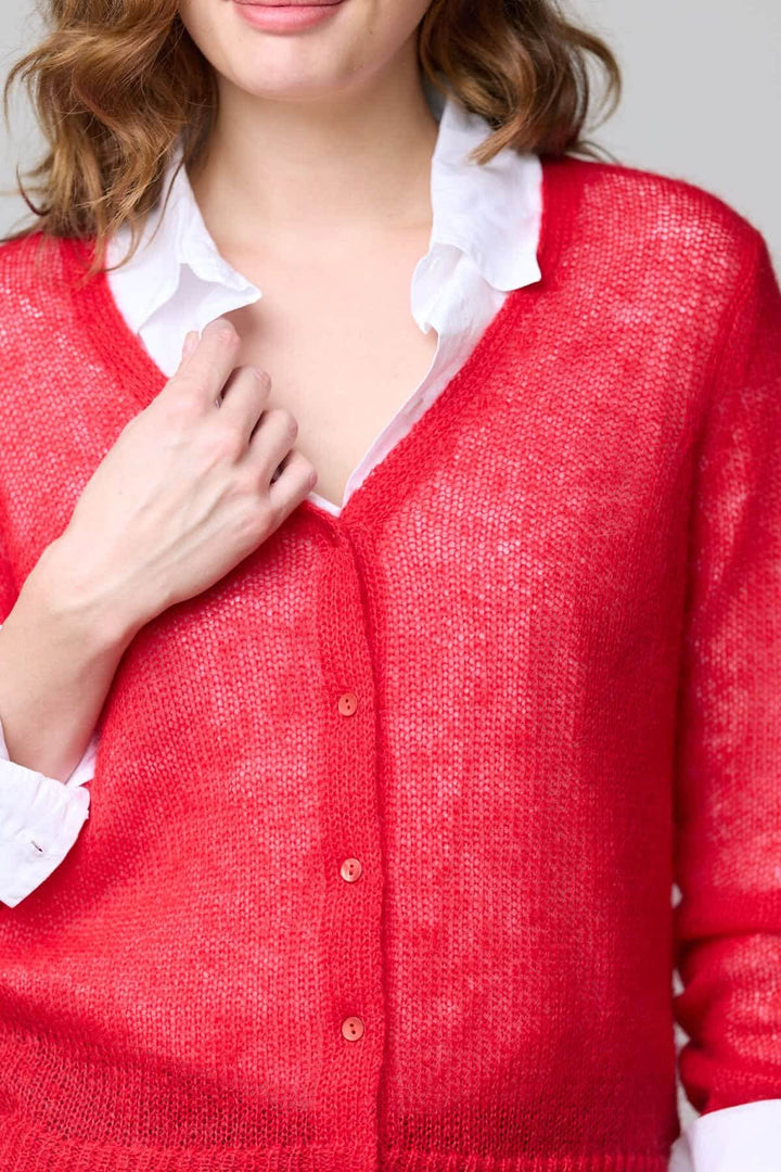 Cardigan en mohair léger rouge avec boutons sur le devant et finition côtelée, porté sur une chemise blanche pour un look élégant.