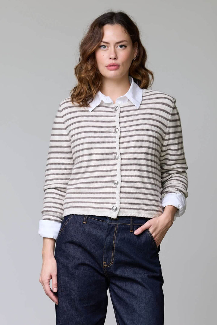 Femme portant un cardigan rayé court à boutons, style marin élégant, superposé sur chemise blanche, idéal pour look chic et décontracté.