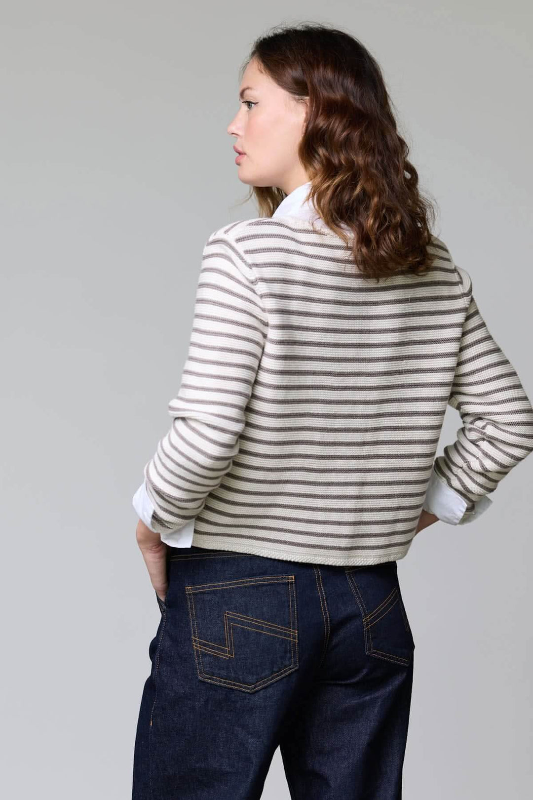 Femme portant un cardigan rayé court à boutons en maille douce, vue de dos, parfait pour un style marin chic et décontracté.