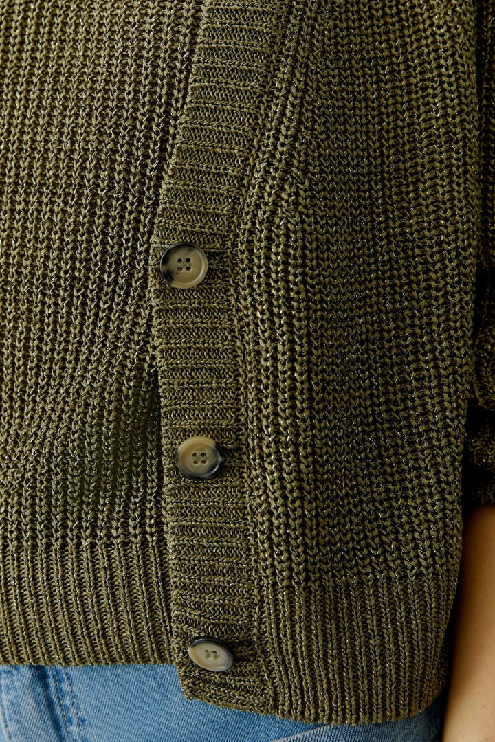 Cardigan tricoté avec fermeture boutonnée, maille verte, porté sur un jean.