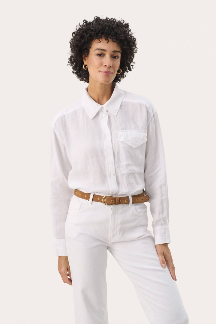 Femme portant une chemise blanche avec une ceinture en suède, élégante et contemporaine.