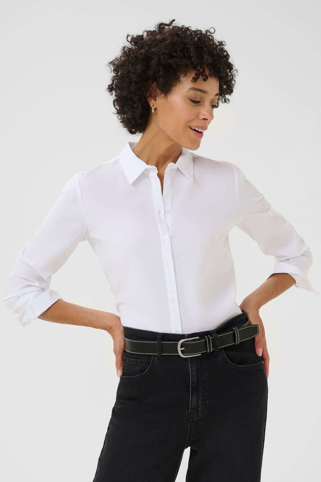 Femme portant la Ceinture Seyra en cuir véritable avec boucle métallique, associée à une chemise blanche et un jean noir.