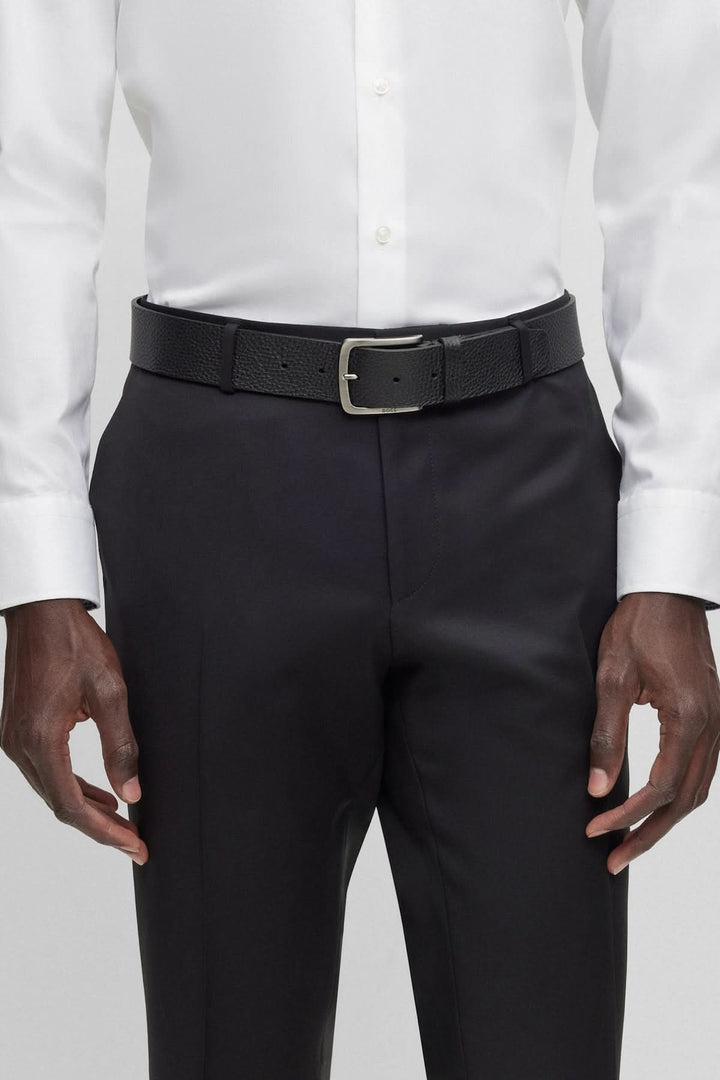 Ceinture en cuir italien à grain portée avec une chemise blanche et un pantalon noir.