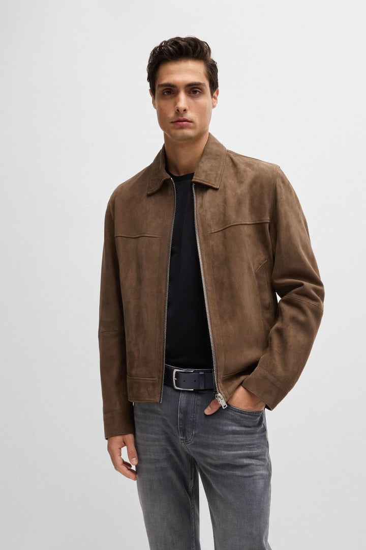 Homme portant une veste en daim marron avec un t-shirt noir et jeans gris, style moderne.