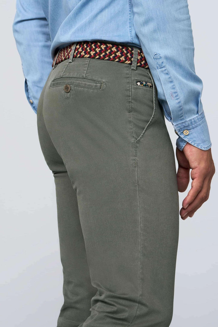 Ceinture tressée colorée portée avec un pantalon vert, ajoutant du style à une tenue décontractée.