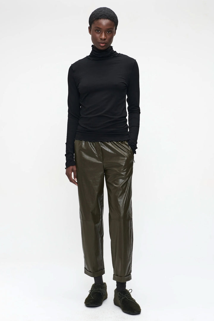 Chandail Janice noir ajusté avec col roulé, porté avec un pantalon vert olive pour un look minimaliste.
