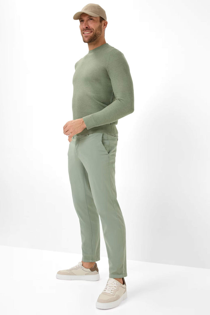 Homme portant un chandail à col rond en maille fine et un pantalon vert, style décontracté et élégant.