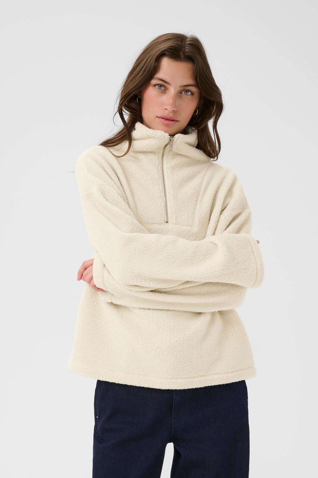 Femme portant un Chandail Sirana en sherpa avec col montant zippé, idéal pour un look cosy. Couleur crème, style décontracté et confortable.