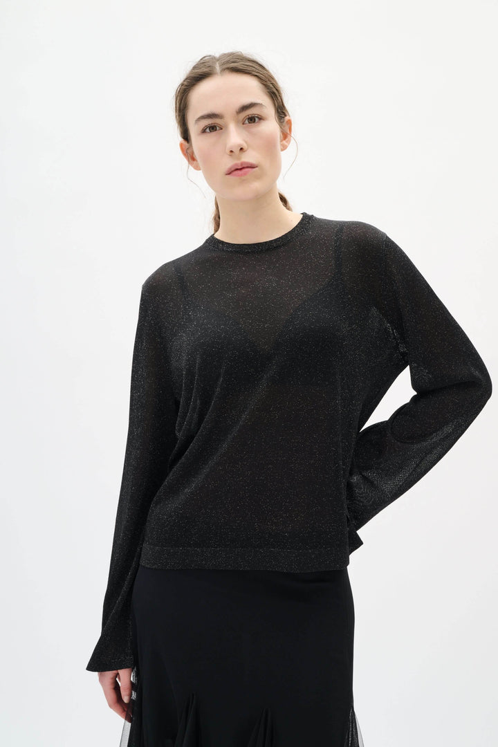 Femme portant le Chandail Thani à effet scintillant, élégant et moderne, légèrement transparent, parfait pour les soirées spéciales.