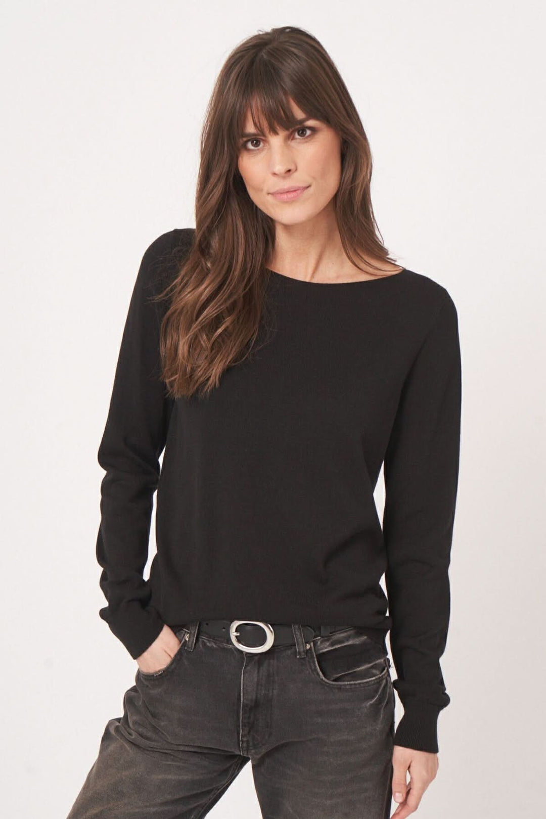 Chandail basique noir à encolure bateau, coupe droite, porté avec un jean pour un look élégant et confortable.