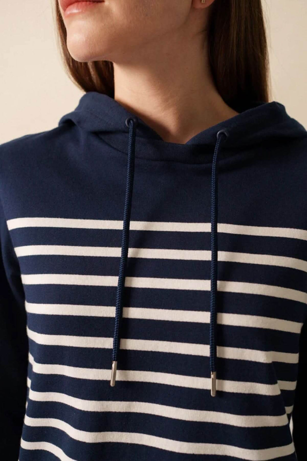 Chandail à capuche marin à rayures horizontales blanches sur fond bleu, style décontracté et moderne.