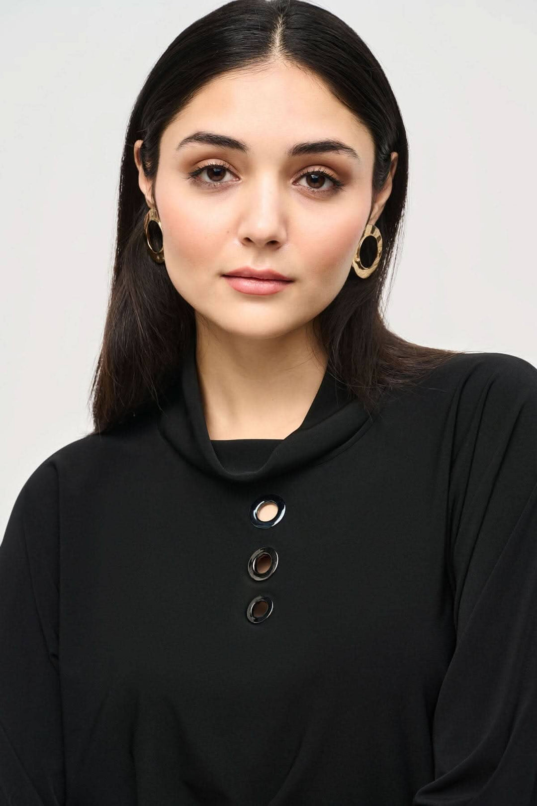 Modèle portant un chandail col bénitier noir avec boutons, mettant en avant un style minimaliste et décontracté.