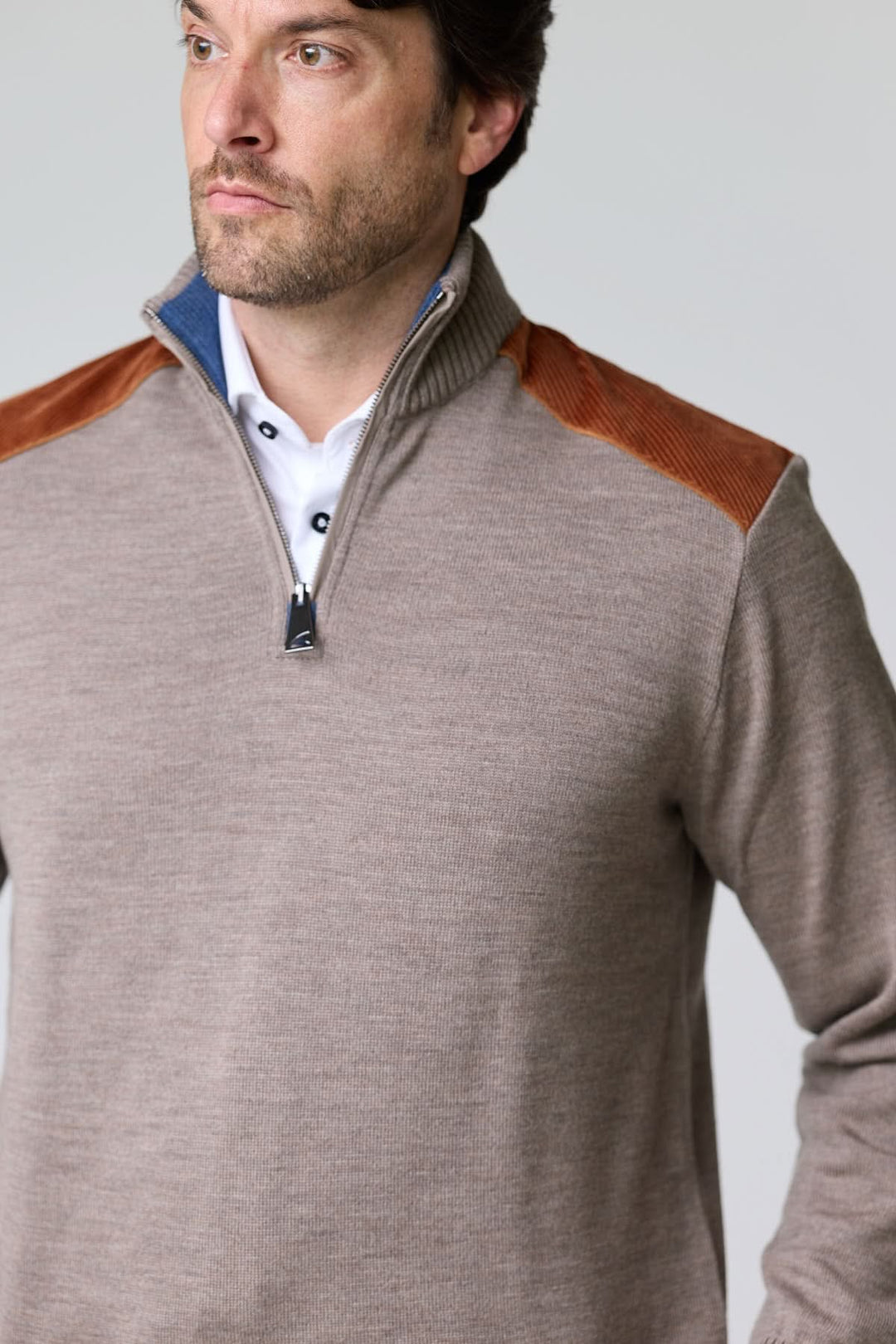 Homme portant un chandail à col demi-glissière avec empiècements en velours côtelé aux épaules, style moderne et décontracté.