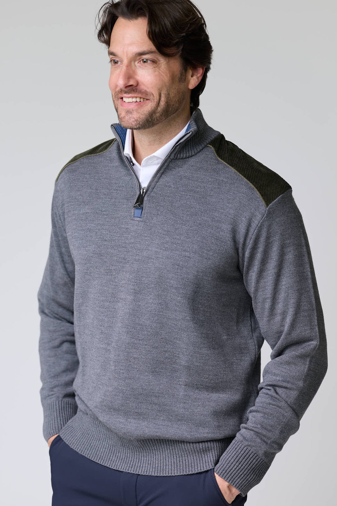 Homme portant un chandail à col demi-glissière avec empiècements contrastants, style décontracté et moderne, maille douce et extensible.