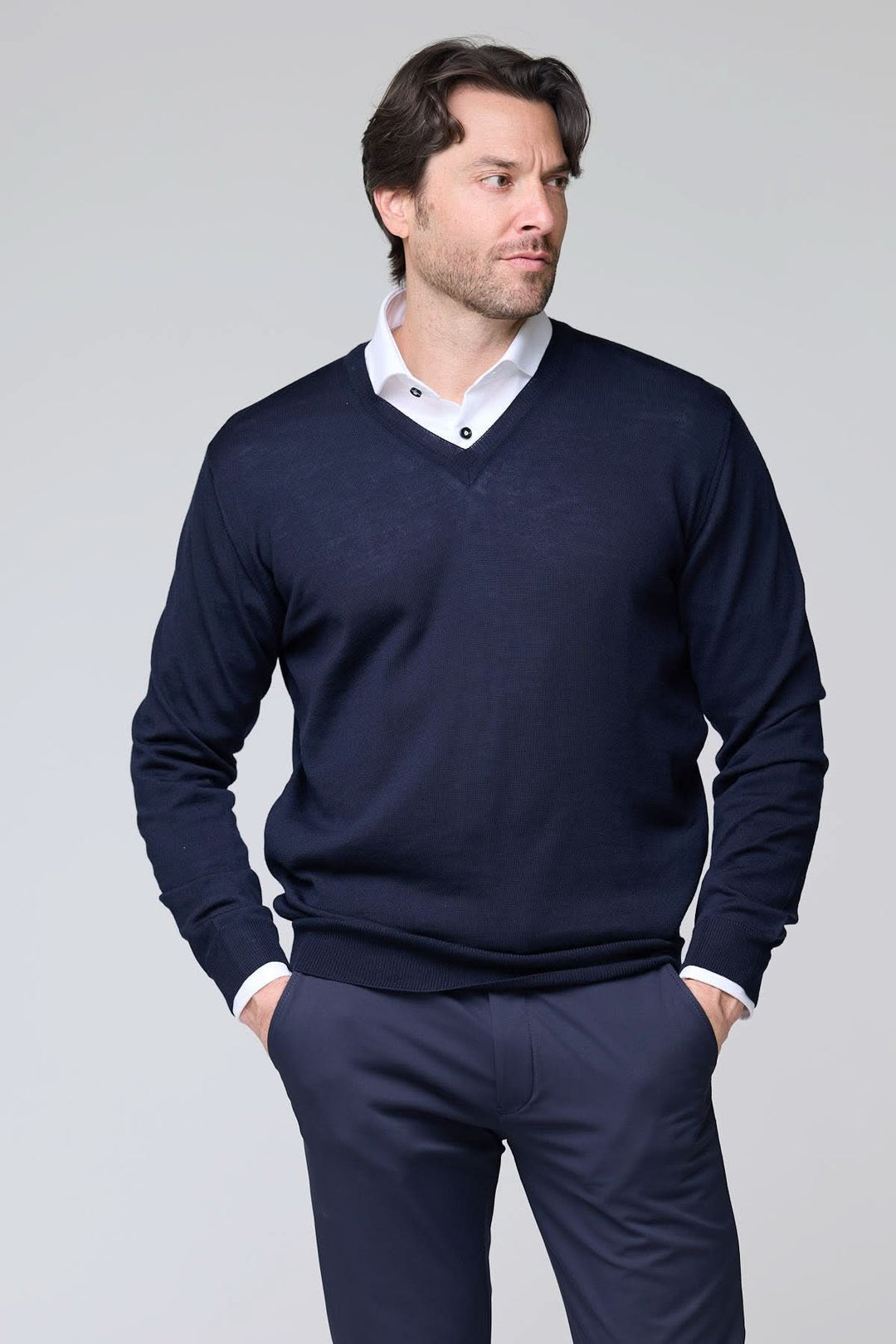 Homme portant un chandail col en V en laine mérinos, couleur marine, avec chemise blanche, style élégant et intemporel, 100% laine mérinos.