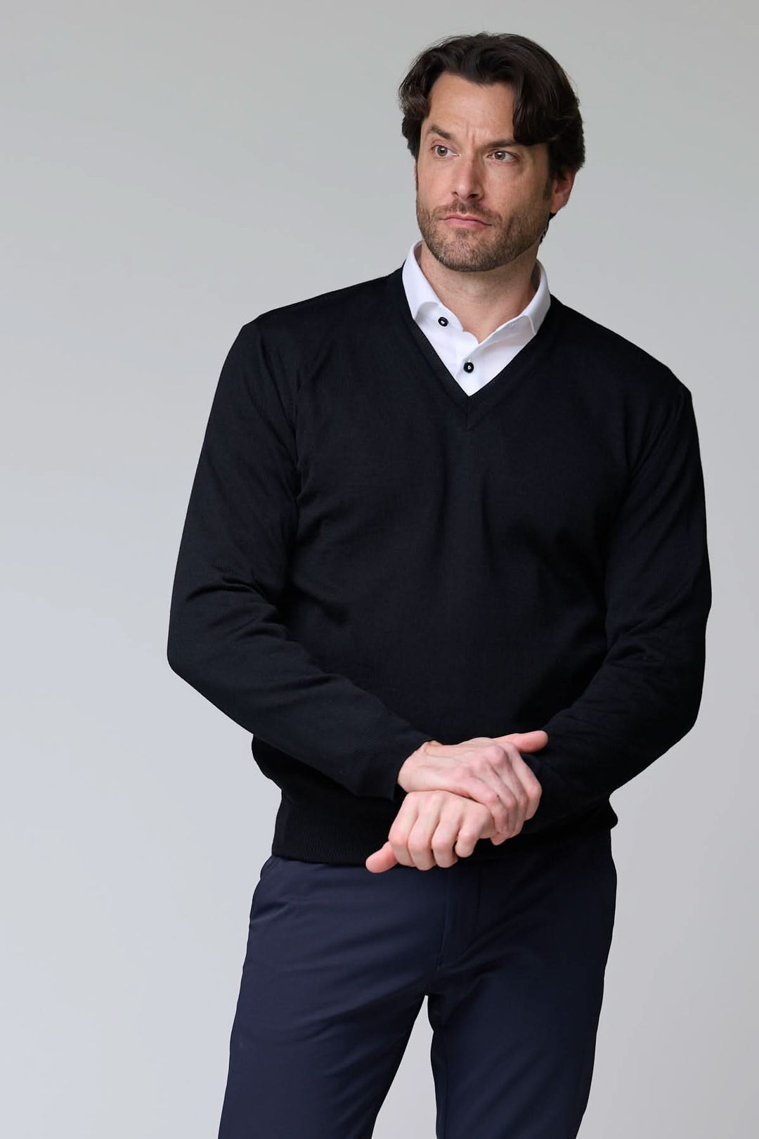 Homme portant un chandail col en V en laine mérinos noir sur chemise blanche élégante