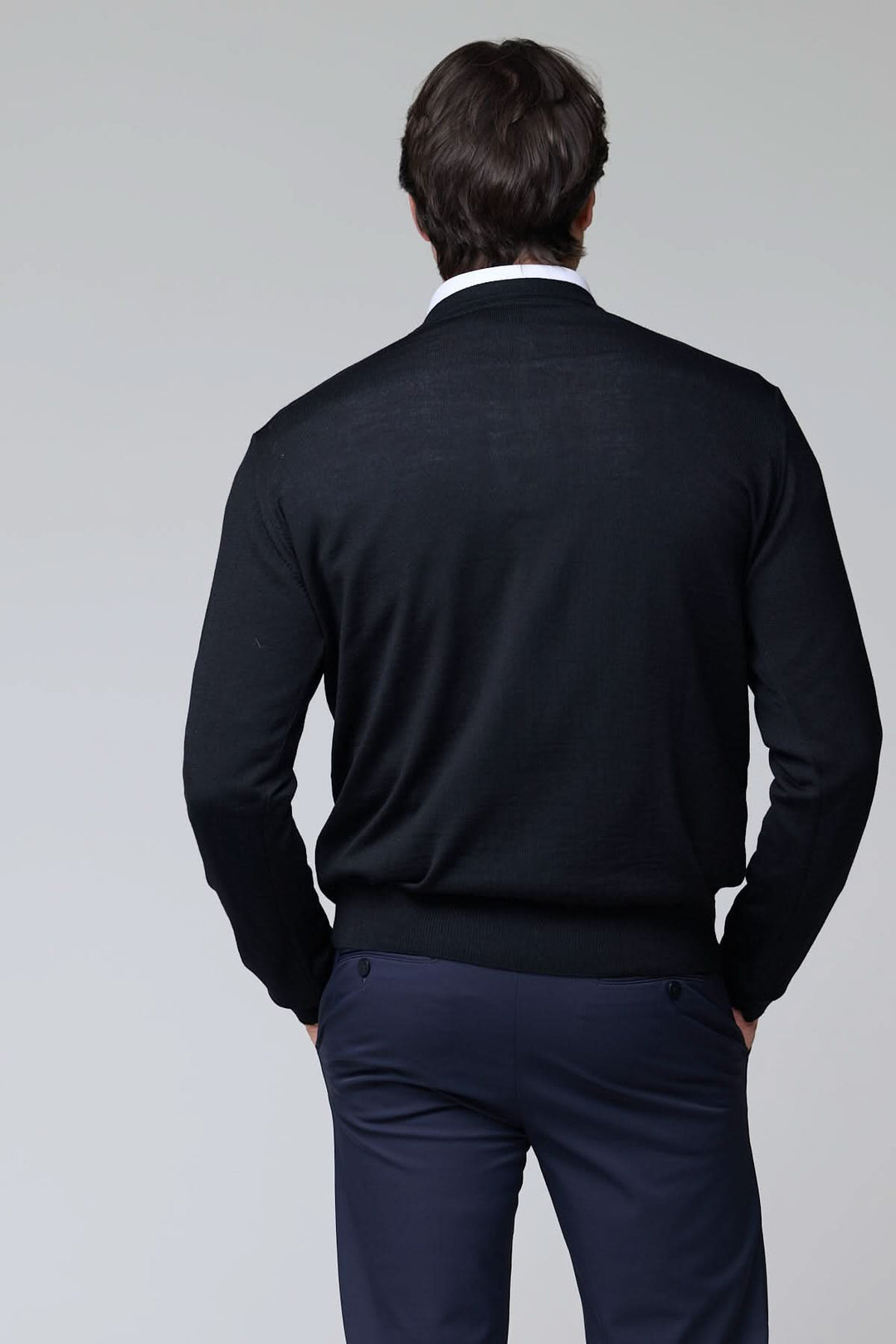 Alt Tag: Homme portant un chandail col en V en laine mérinos noire, vue arrière, styled sur une chemise blanche pour un look élégant.