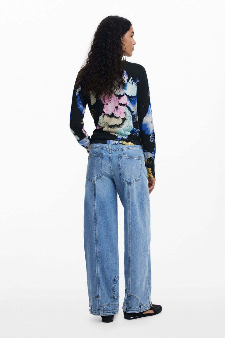 Femme portant un chandail à col rond avec imprimé floral, vue arrière, associé à un pantalon taille haute pour un style équilibré.