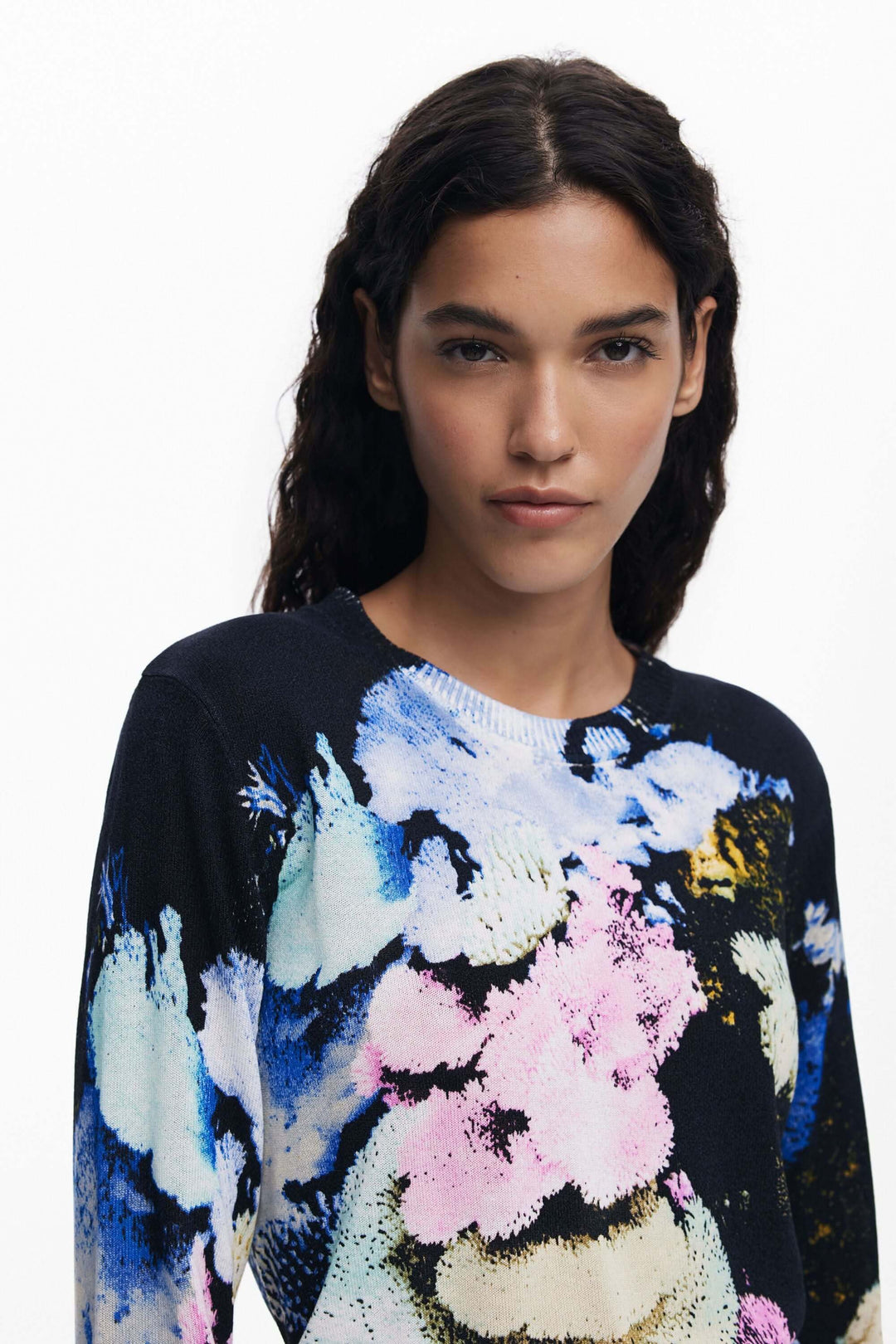 Femme portant un chandail à col rond avec imprimé floral abstrait coloré sur un fond noir.