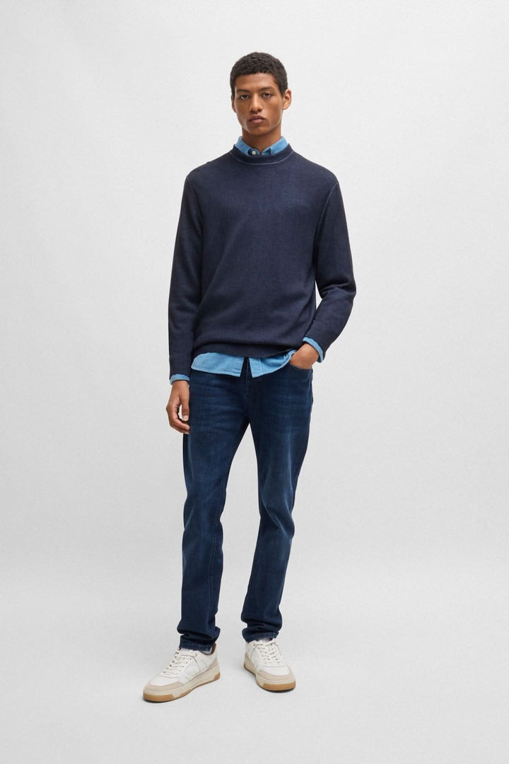 Homme portant un chandail col rond en laine navy avec une chemise bleu en dessous et un jean, style décontracté.