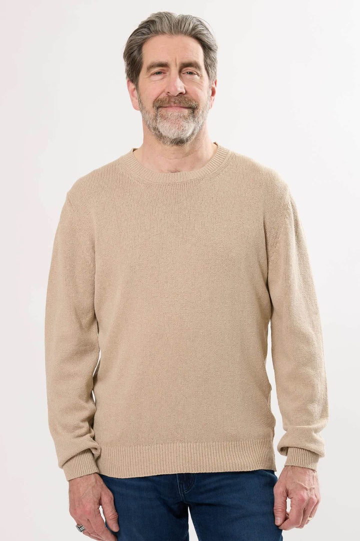 Homme portant un chandail à col rond en tricot texturé beige, style décontracté et confortable.