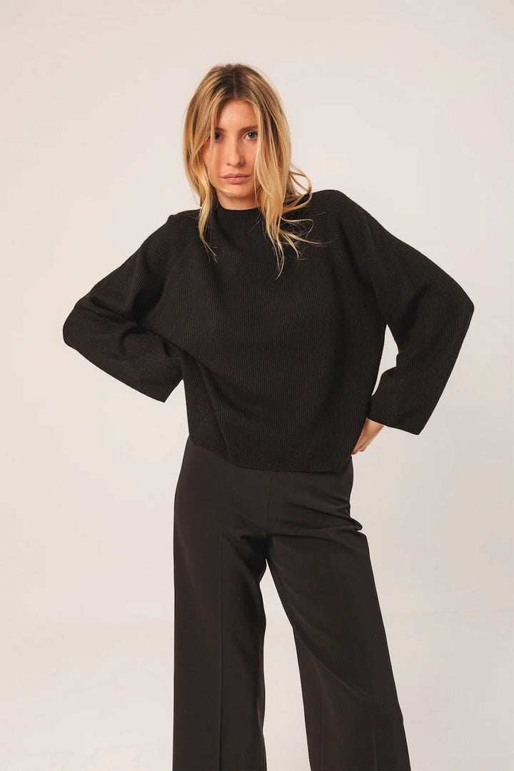 Chandail côtelé noir à coupe ample avec manches longues, style chic et décontracté.