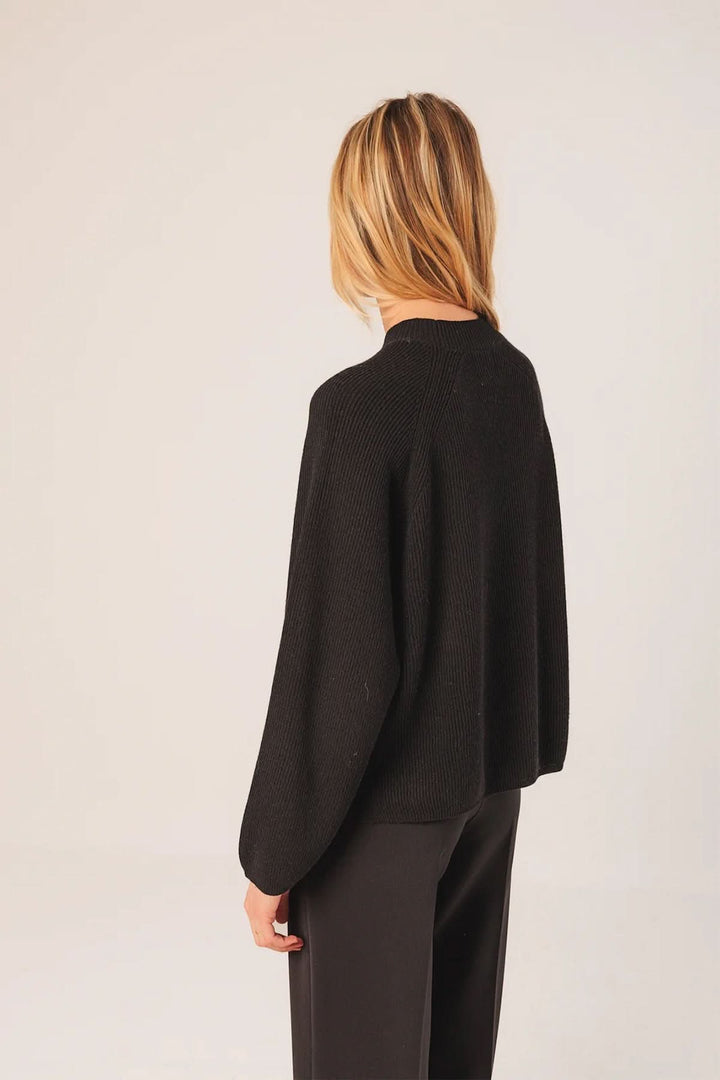 Chandail côtelé noir à coupe ample et confortable, parfait pour un look chic ou décontracté.