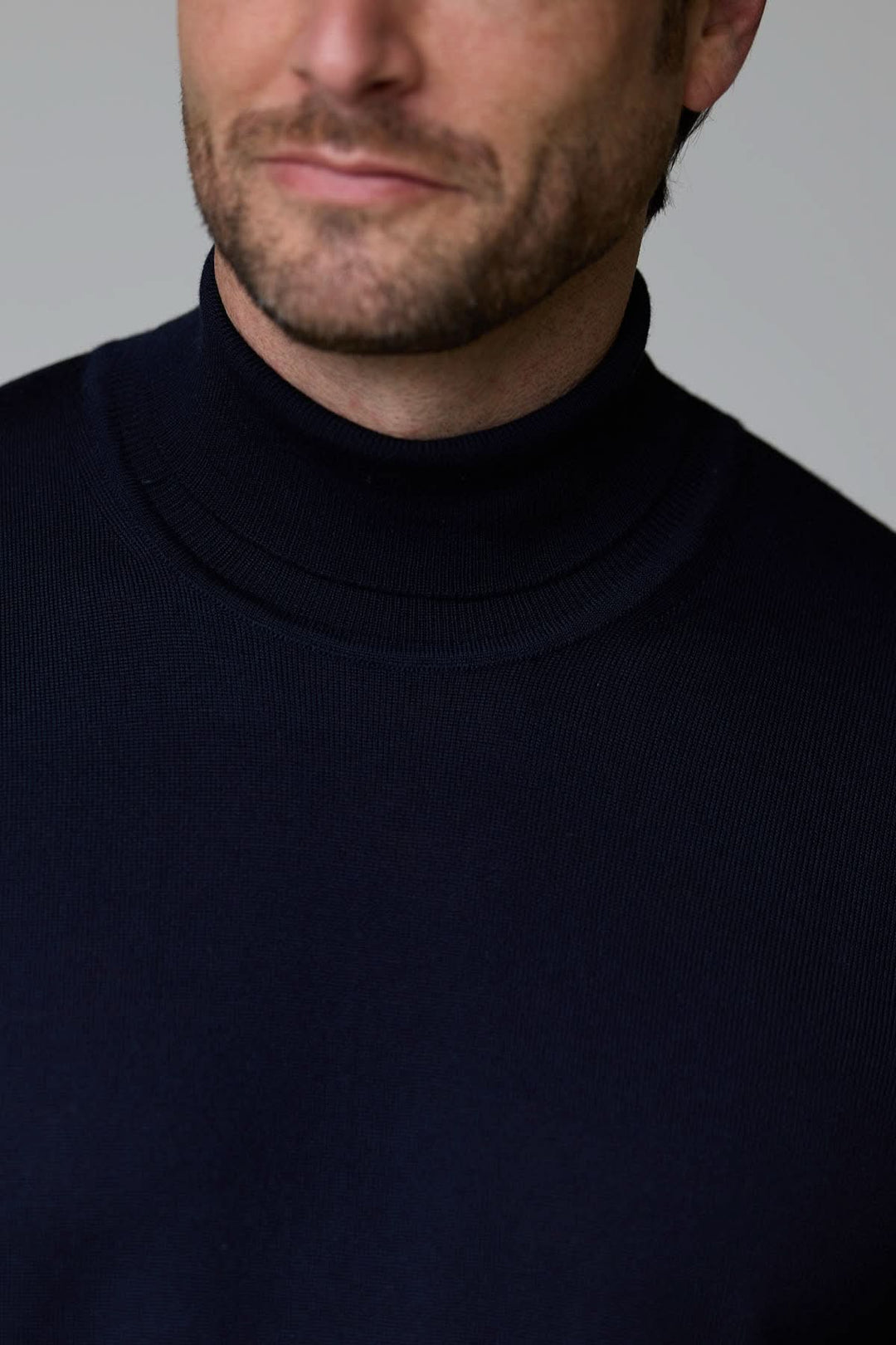 Homme portant un chandail en laine mérinos fine bleu marine à col roulé, style intemporel et élégant.
