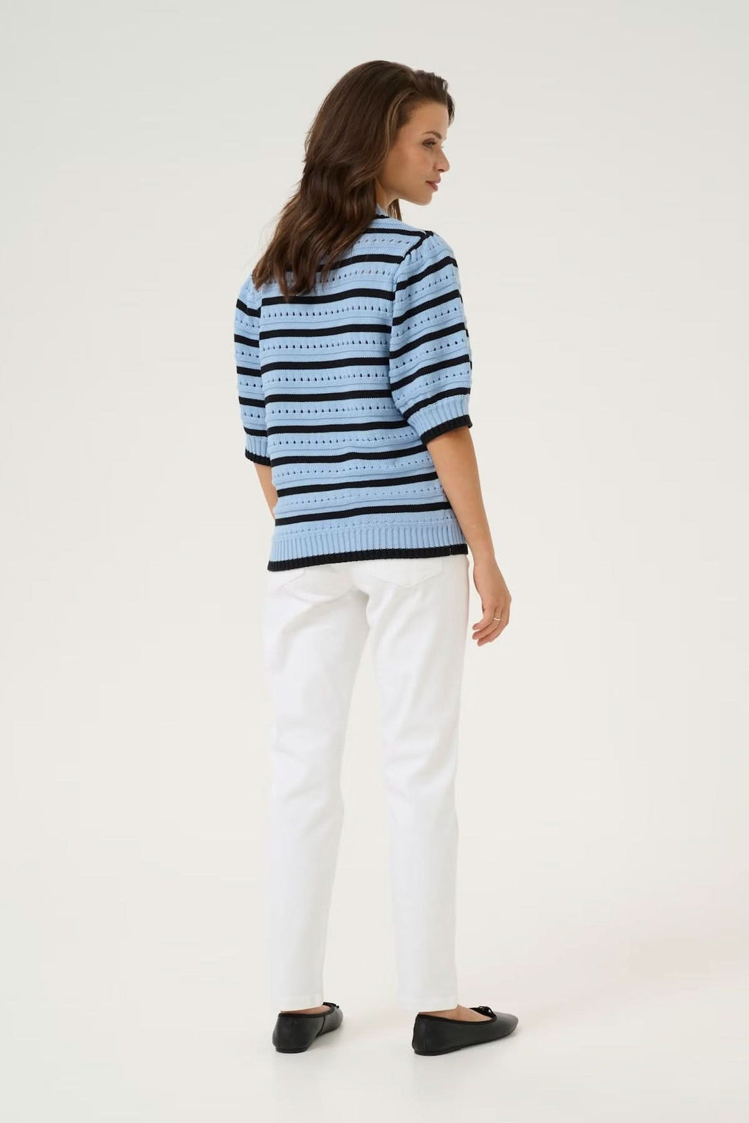 Chandail en maille ajourée rayé bicolore, vue arrière, associé à un pantalon blanc décontracté.