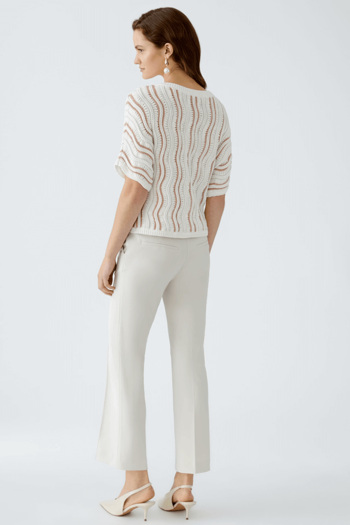 Chandail en maille texturée avec motif ondulé, porté avec un pantalon clair, vue arrière, look décontracté et moderne.