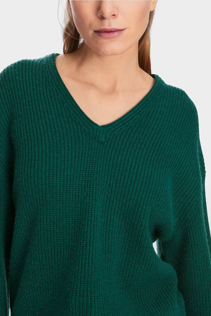 Chandail en mailles vert avec col en V, coupe large, idéal pour le confort et la chaleur.