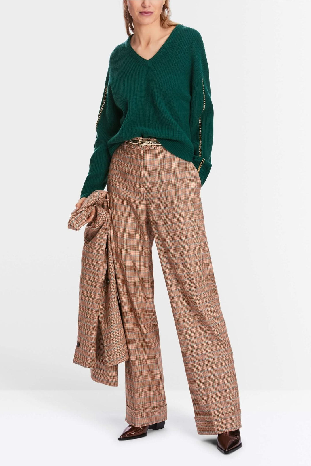 Pull en maille vert avec col en V et pantalon à carreaux larges, look décontracté et stylé.