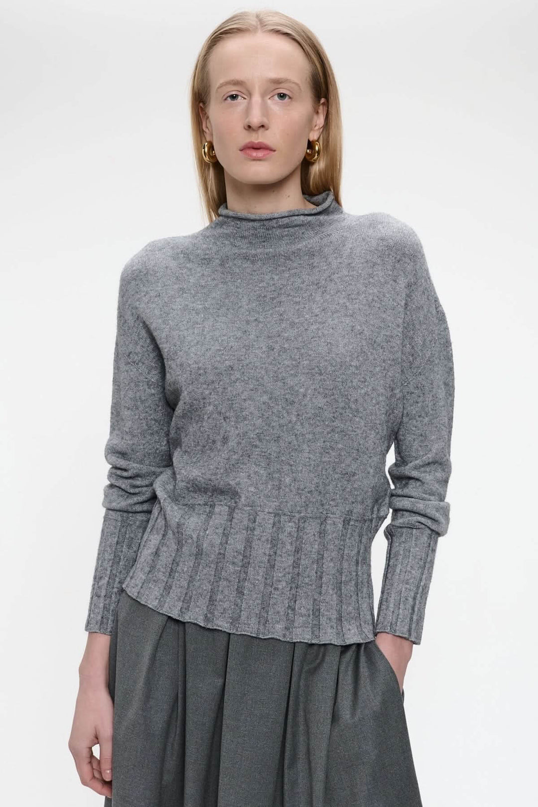 Chandail en tricot gris à encolure montante et manches longues, offrant une allure sophistiquée et moderne. Décris moi le produit en français.