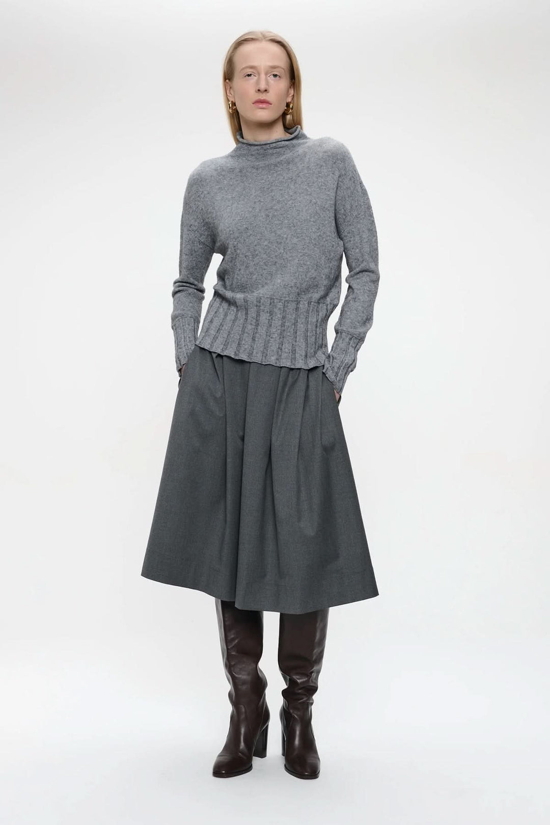 Chandail en tricot gris, coupe droite, manches longues, encolure roulée, porté par une femme, créer une allure sophistiquée.