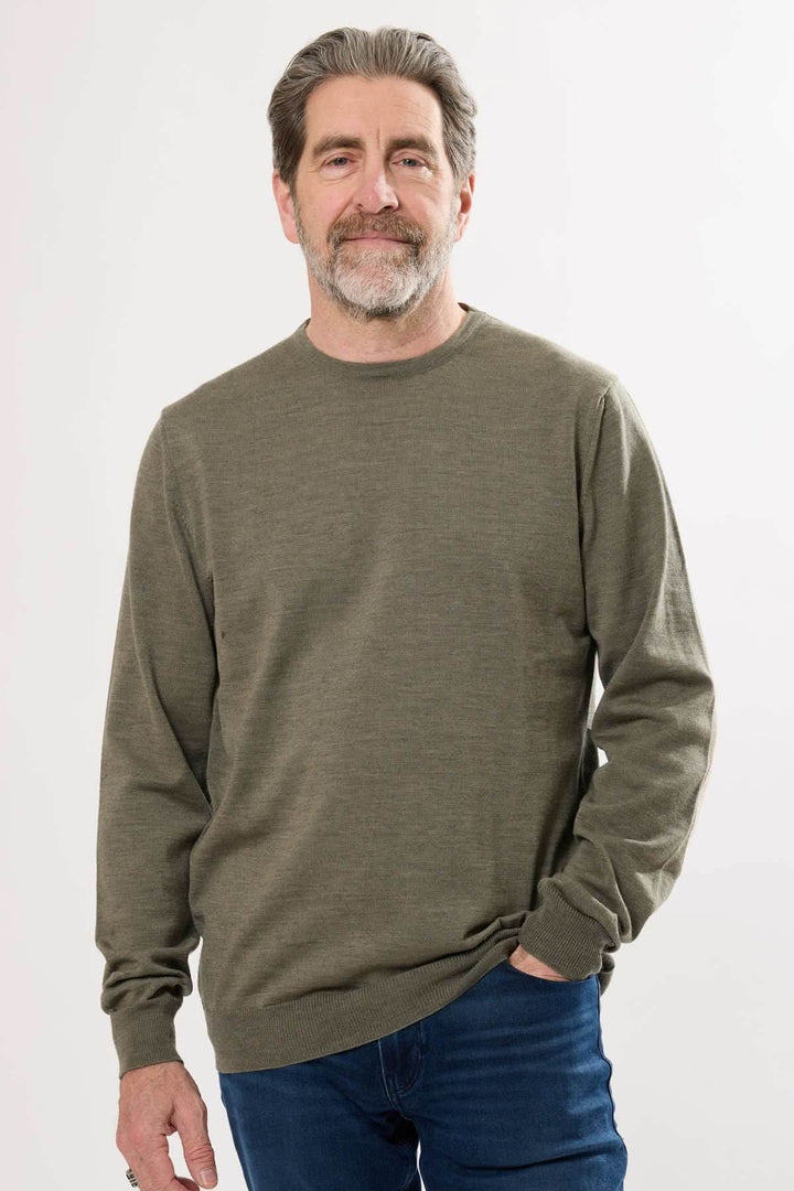 Homme portant un chandail en tricot olive avec col rond et manches longues pour un style décontracté.