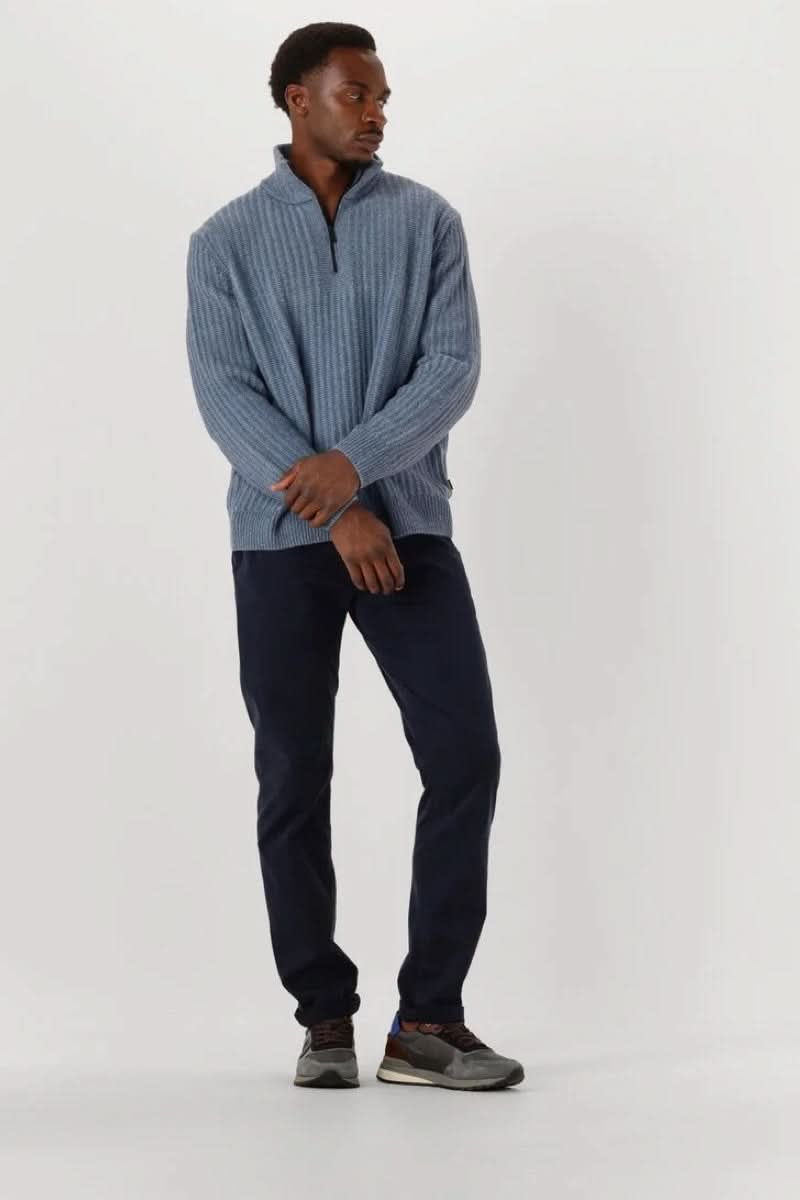 Homme portant un chandail en tricot à demi-glissière bleu, style décontracté et soigné avec col montant zippé, sur un fond neutre.