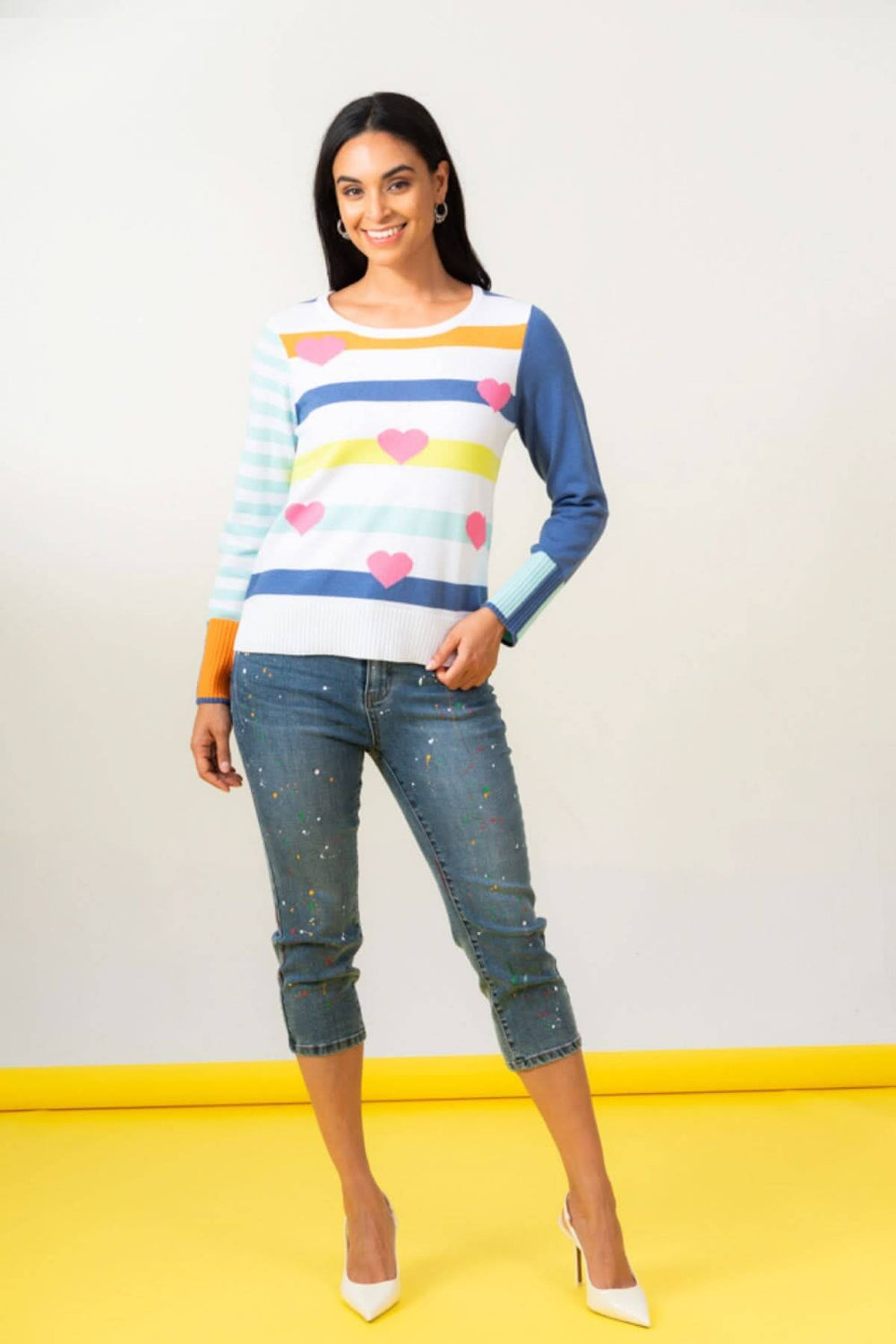 Chandail imprimé coeurs avec manches lignée et un look asymétrique, porté avec un jean décontracté.