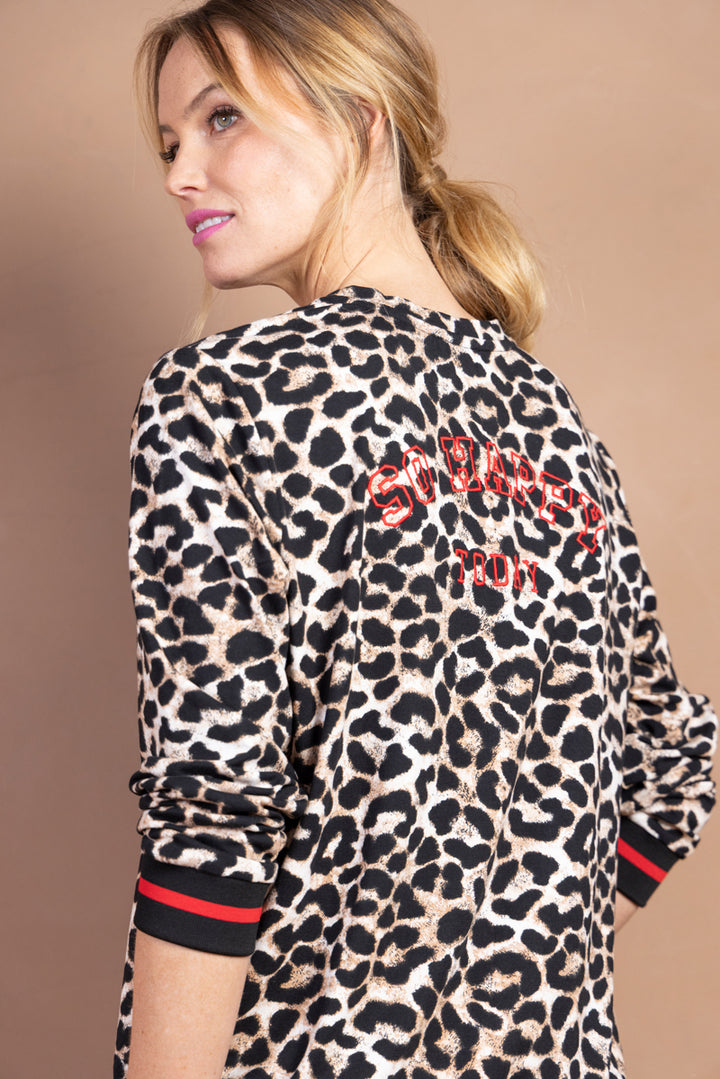 Femme portant un chandail imprimé léopard avec finitions contrastantes, look moderne et sportif.