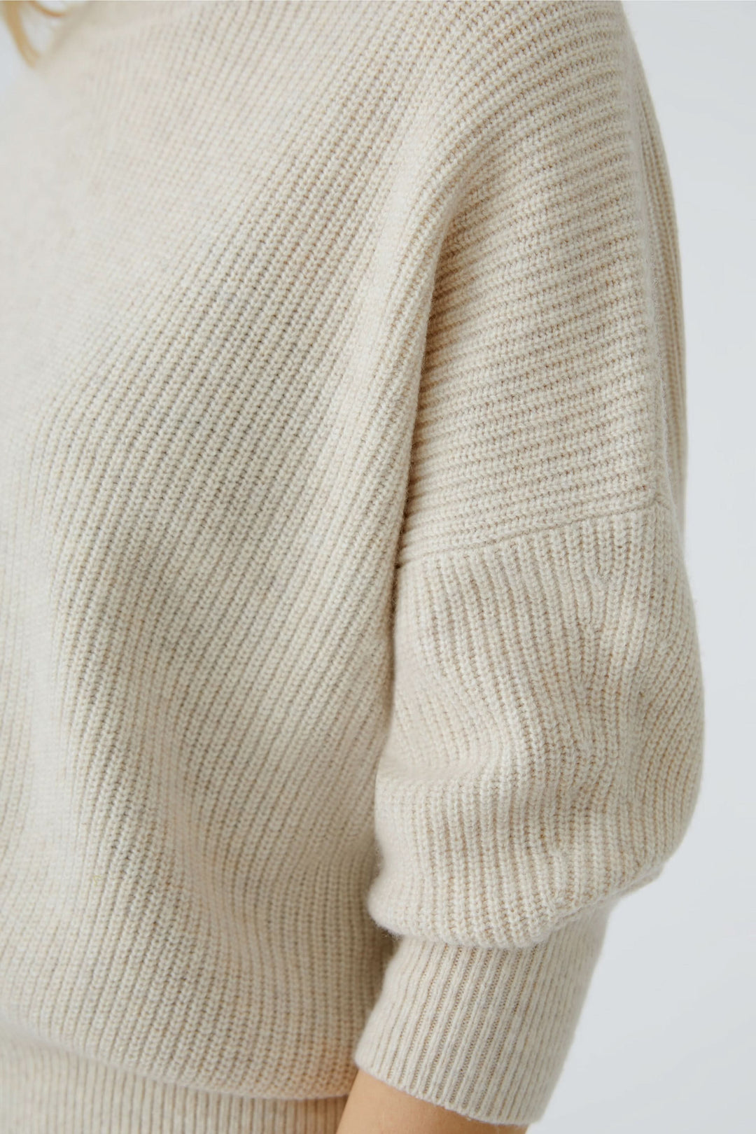 Chandail maille fine beige à manches longues et col montant élégant avec finitions côtelées pour un style minimaliste et confortable.