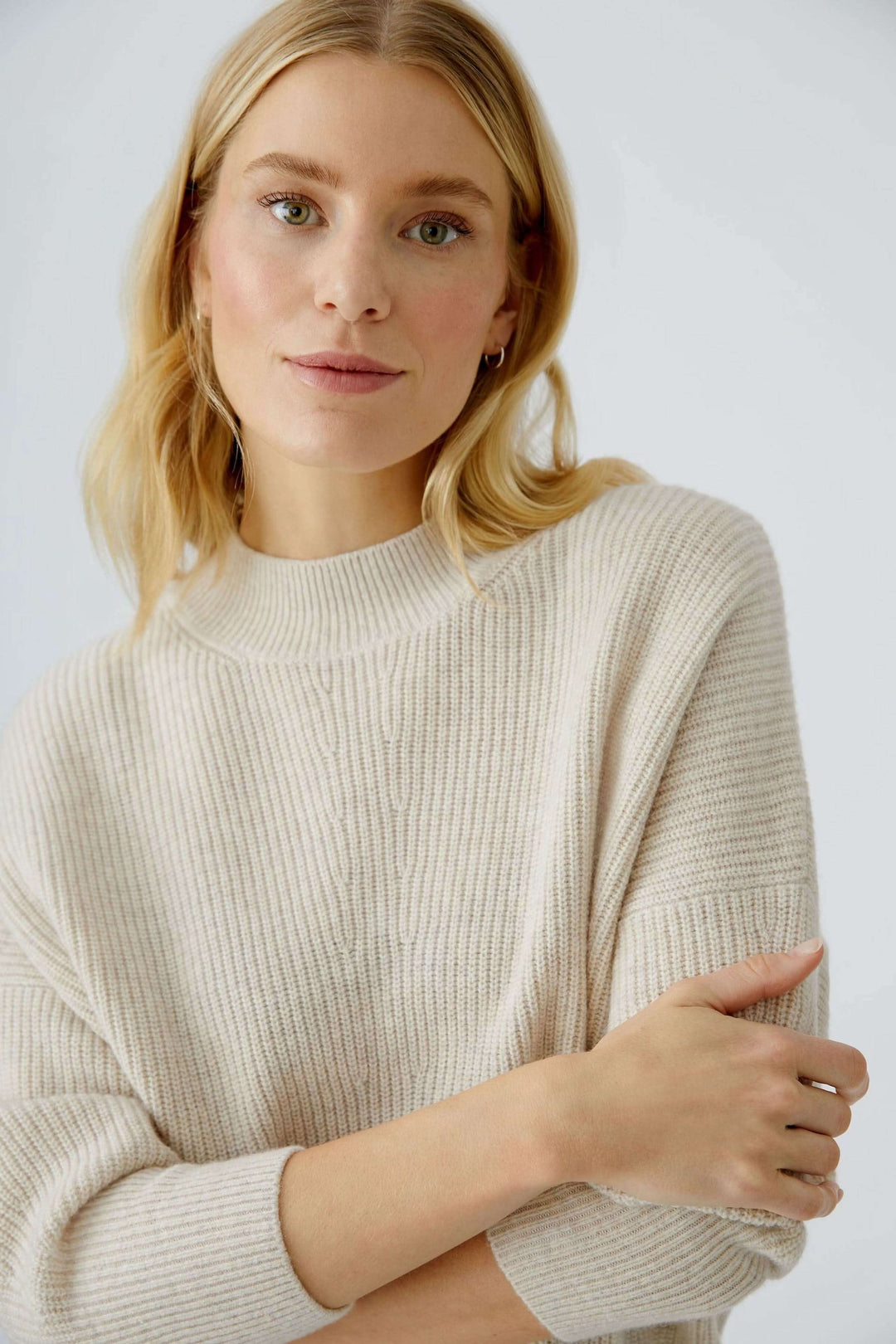Femme portant un chandail maille fine beige à col montant pour un look élégant et sophistiqué.